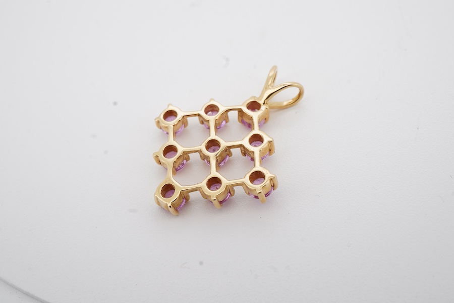 A recent 18ct gold and nine stone pink sapphire set diamond shaped pendant, overall 23mm, gross weight 2.6 grams.